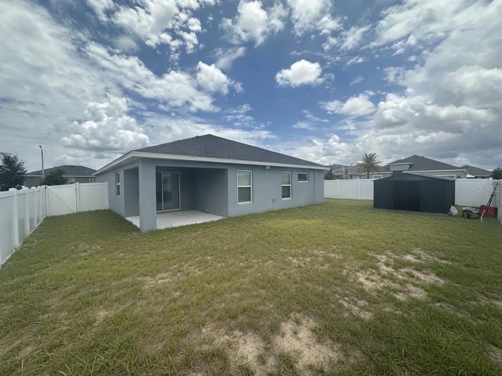 The exterior view shows the back of a gray house with a covered patio — 1032 ZION DRIVE, HAINES CITY, FL