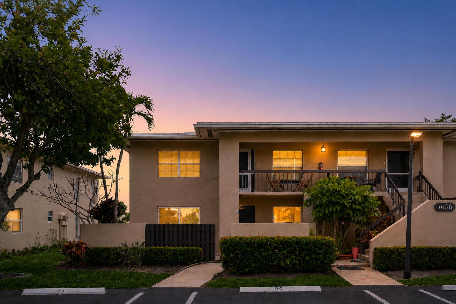 A two-story apartment building exterior features a balcony, stairs, and a parking lot at dusk — 5656 Via Delray Boulevard, Delray Beach FL 33484, DELRAY BEACH, FL