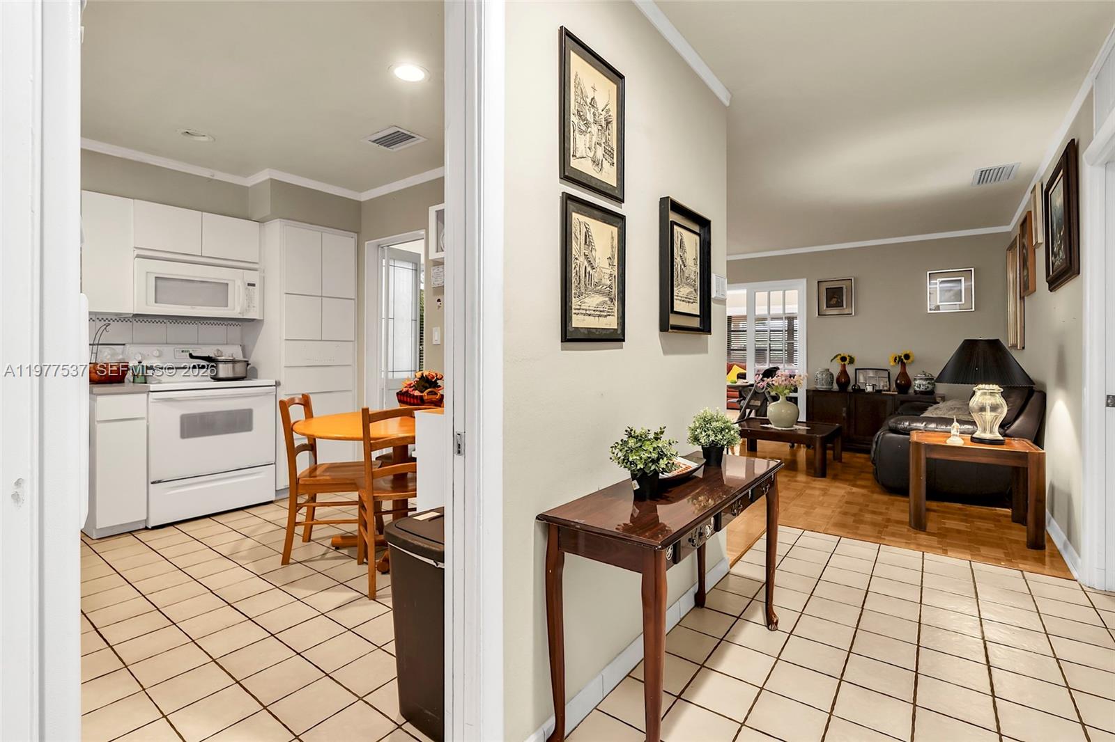 A view from a tiled entryway looking into a kitchen and a living room — 9011 SW 18th Ter, Miami FL 33165, MIAMI, FL