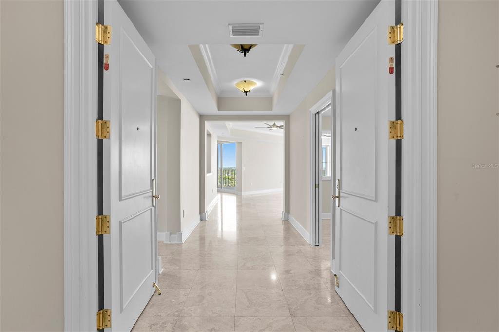 A view through double doors into a tiled hallway leading to a bright living area — 300 BEACH DRIVE NE UNIT 1201, ST PETERSBURG, FL
