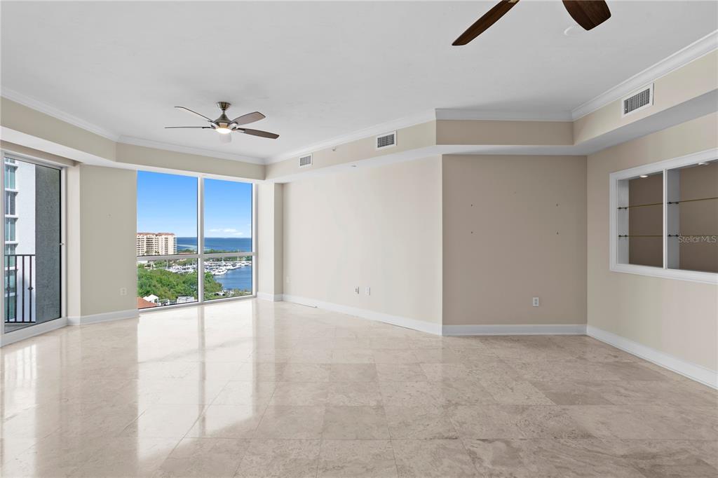 An empty room with light tile floors, a ceiling fan, and large windows overlooking water — 300 BEACH DRIVE NE UNIT 1201, ST PETERSBURG, FL