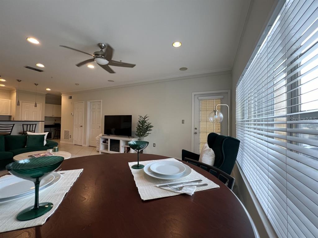 A dining area with a round wooden table overlooks a living room with a television — 4307 BAYSIDE VILLAGE DRIVE UNIT 201, TAMPA, FL
