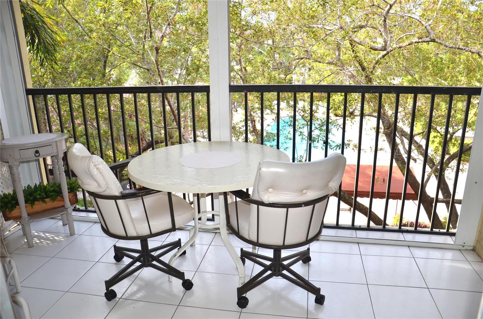 A balcony with a round table, two swivel chairs, and a view of trees and water — 255 S Cypress Road # 342, Pompano Beach FL 33060, POMPANO BEACH, FL