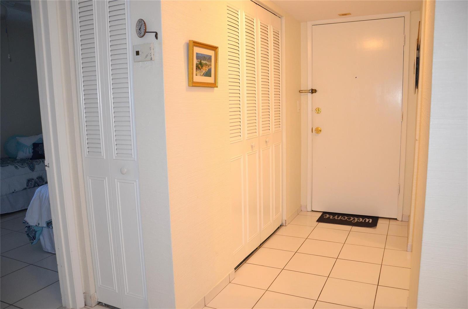 A tiled entryway features a white front door, louvered closet doors, and a framed wall picture — 255 S Cypress Road # 342, Pompano Beach FL 33060, POMPANO BEACH, FL