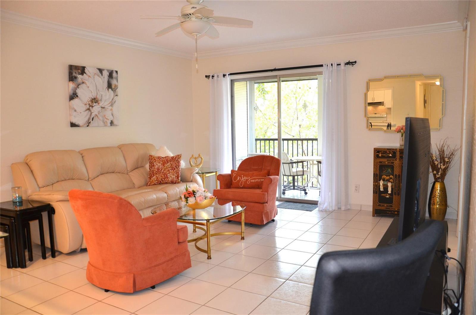 A living room features tile flooring, a beige sofa, two orange armchairs, and a balcony — 255 S Cypress Road # 342, Pompano Beach FL 33060, POMPANO BEACH, FL