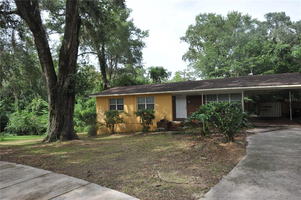A single-story house with yellow siding, a brick facade, and an attached carport — 1410 NW 7TH ROAD, GAINESVILLE, FL