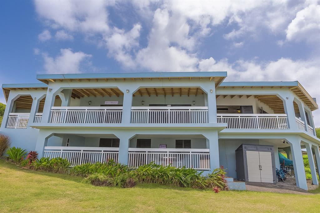 A two-story light blue house with white railings and a grassy yard under a cloudy sky — Calle 250 PLAYA SARDINERA II, CULEBRA, PR