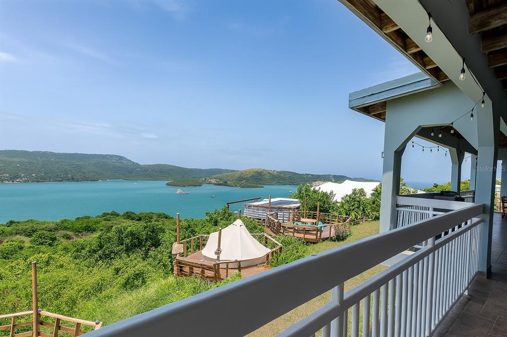 A balcony overlooks a hillside with a tent, a wooden deck, and a bay — Calle 250 PLAYA SARDINERA II, CULEBRA, PR
