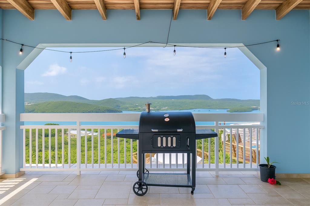 A covered balcony features a black grill, white railing, and a scenic view of water — Calle 250 PLAYA SARDINERA II, CULEBRA, PR
