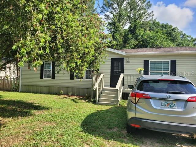 A light-colored single-story house with a front porch and a car parked in the yard — 1385 NW 85TH STREET, OCALA, FL