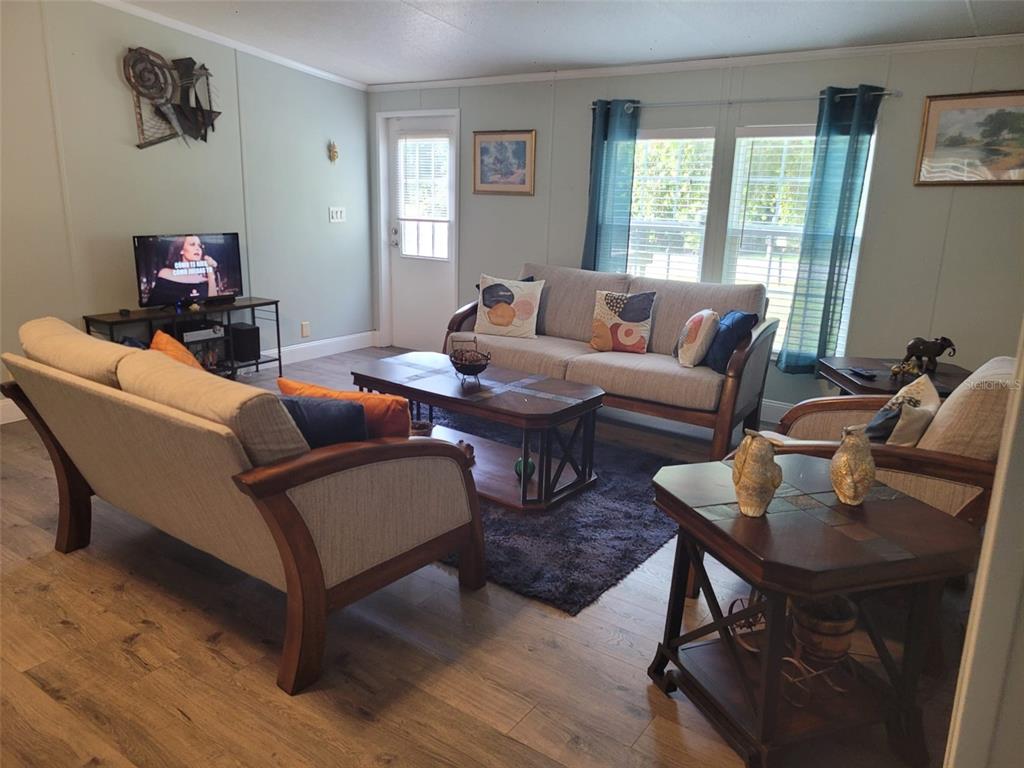 A living room features light green walls, wood-look flooring, two sofas, and a central coffee table — 1385 NW 85TH STREET, OCALA, FL