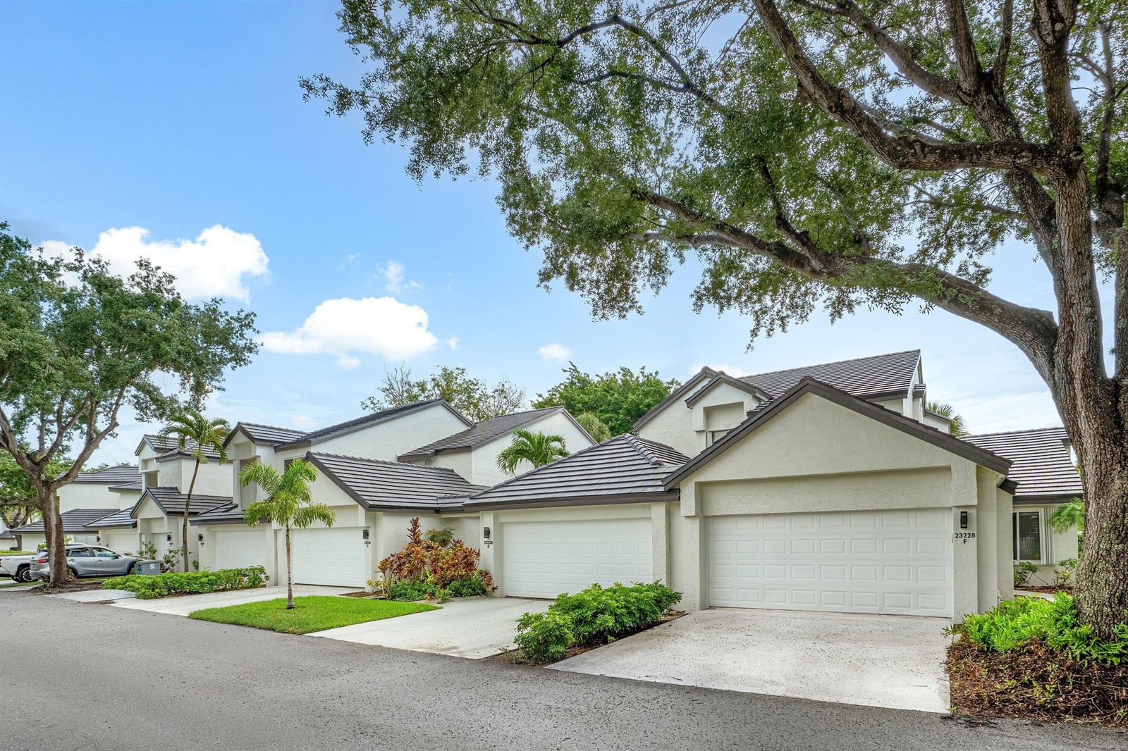 A row of attached townhomes with white stucco walls, dark tile roofs, and private garages — 23140 Island View # 1, Boca Raton FL 33433, BOCA RATON, FL