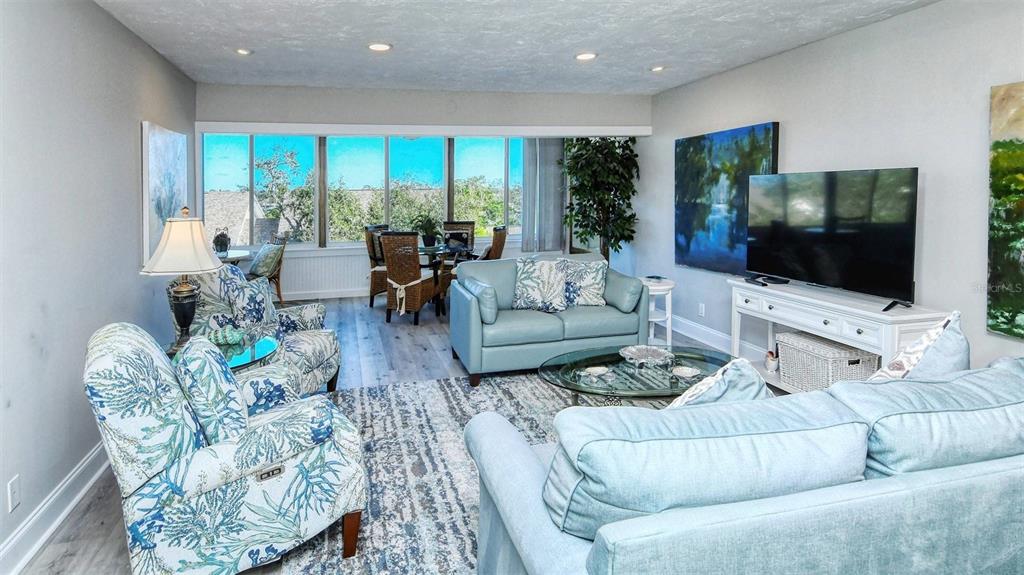A living room features light blue furniture, a patterned area rug, and a dining area — 1255 E PEPPERTREE DRIVE UNIT 305, SARASOTA, FL
