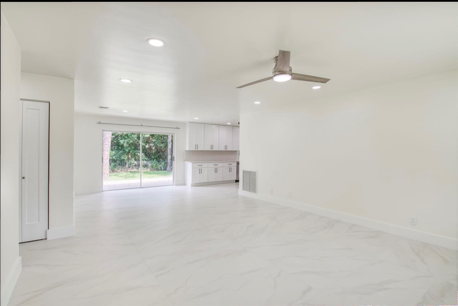 An open-concept room with white walls, marble-look tile flooring, a ceiling fan, and a kitchen — 14735 Flamingo Road, FL 33470, FL