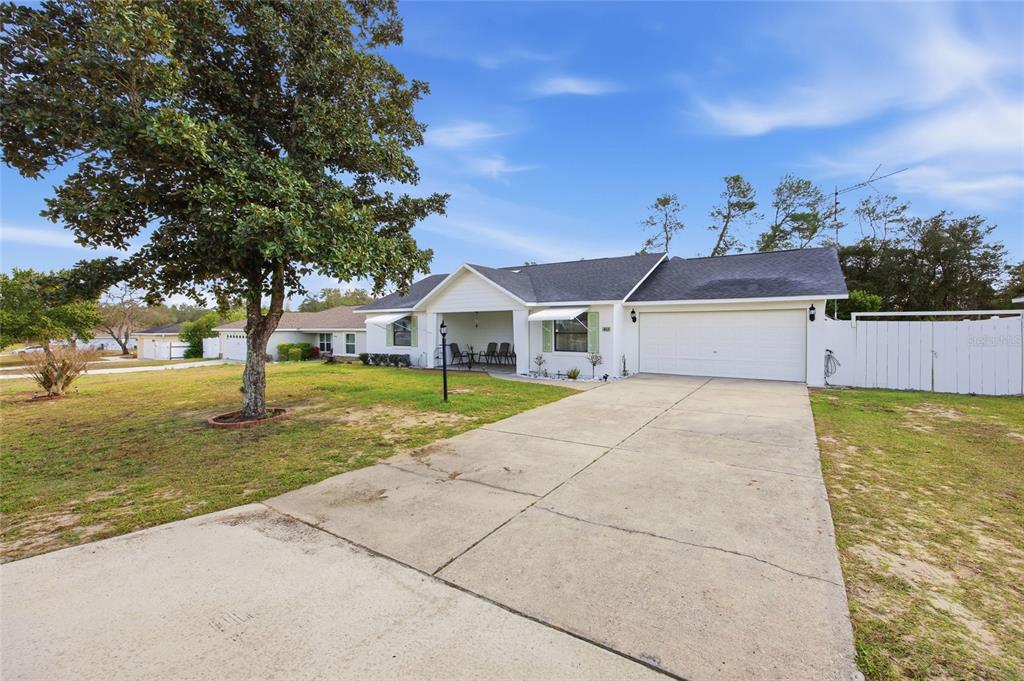 A white single-story house with a two-car garage, covered entryway, and a large front tree — 465 MARION OAKS BOULEVARD, OCALA, FL