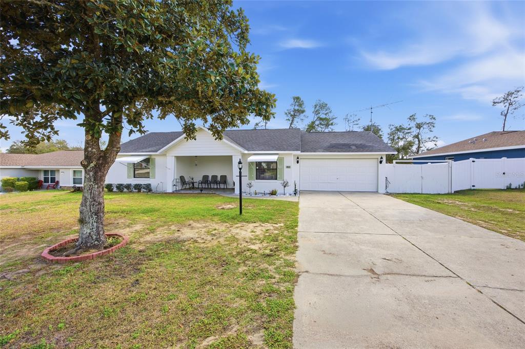 A single-story house with a white exterior, a covered front porch, and a concrete driveway — 465 MARION OAKS BOULEVARD, OCALA, FL