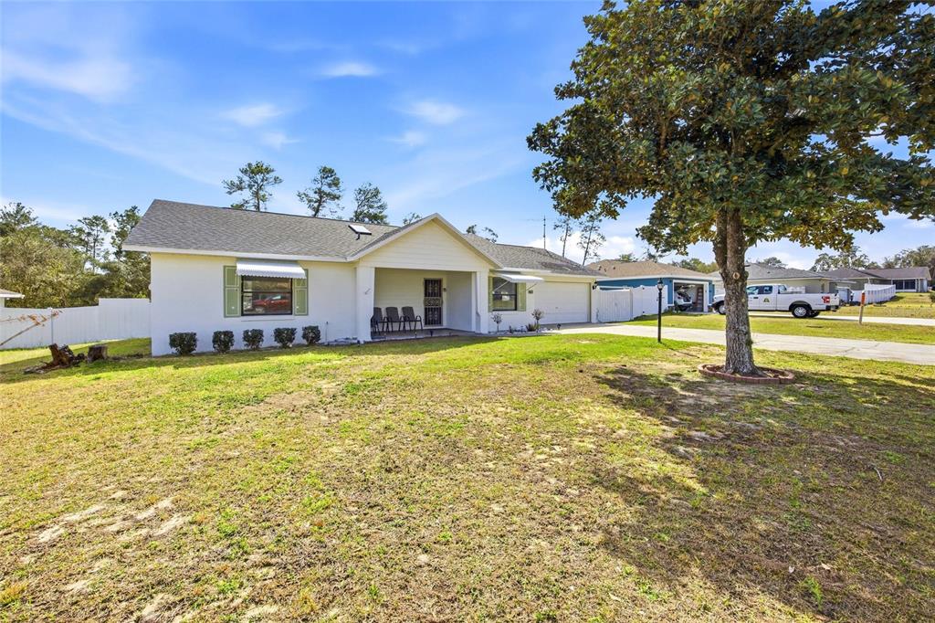 A single-story white house with a covered front porch and a large front yard — 465 MARION OAKS BOULEVARD, OCALA, FL