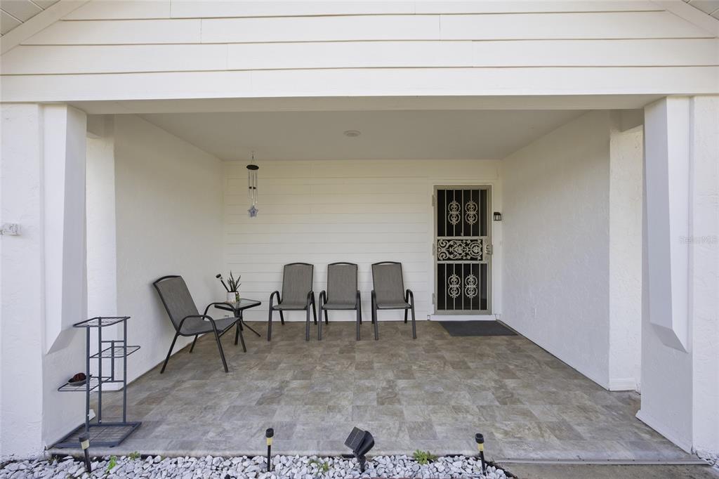 A covered patio features tiled flooring, four chairs, a small table, and a security screen door — 465 MARION OAKS BOULEVARD, OCALA, FL