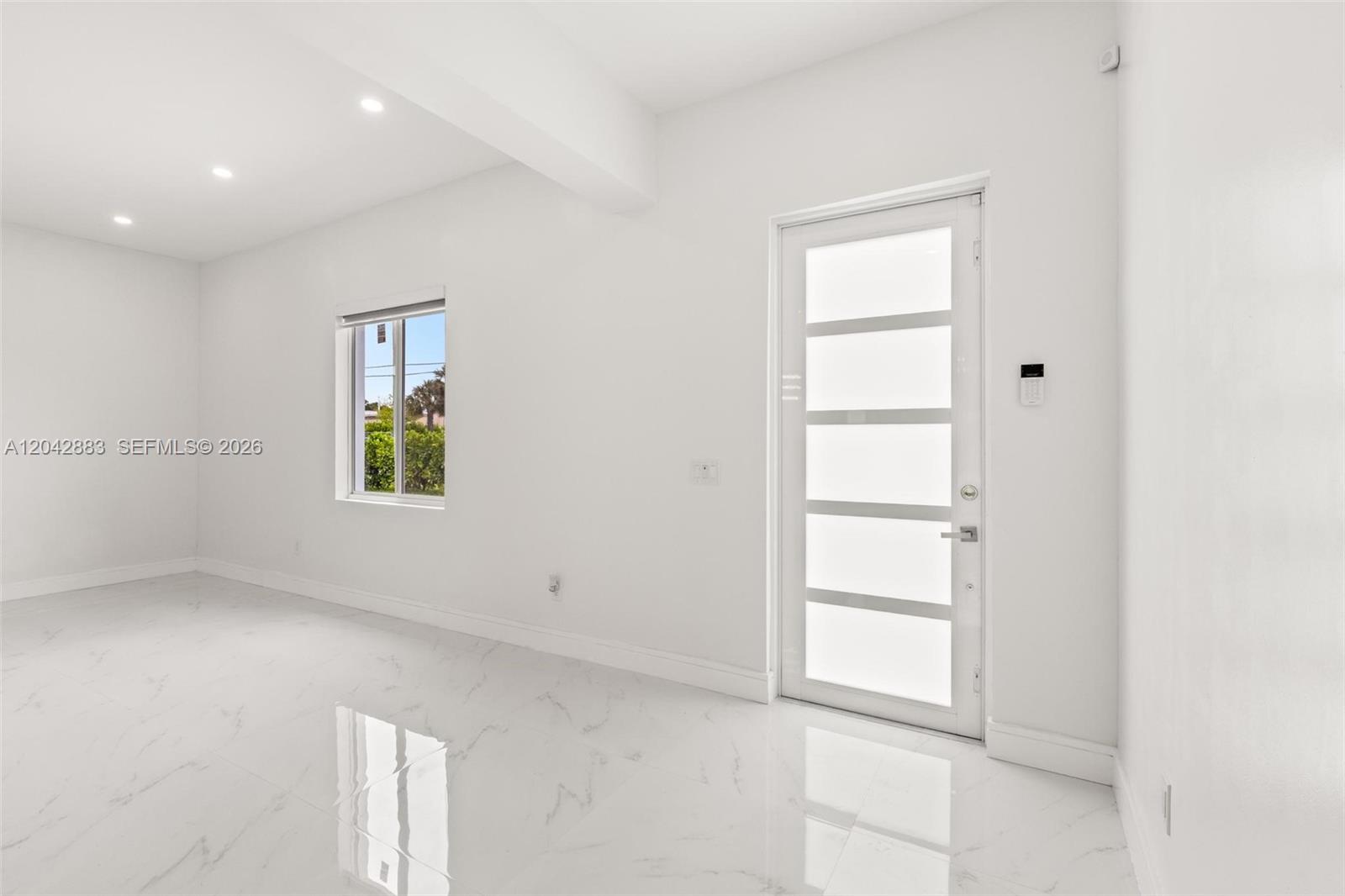 A bright, minimalist room features white walls, marble-style flooring, and a modern glass-paneled door — 14801 NW 5th Ave, Miami FL 33168, MIAMI, FL