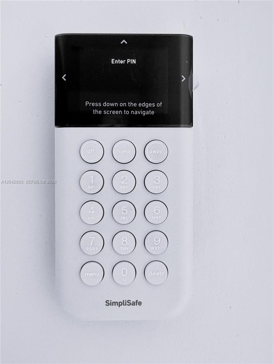 A white SimpliSafe security system keypad is mounted on a plain white wall — 14801 NW 5th Ave, Miami FL 33168, MIAMI, FL