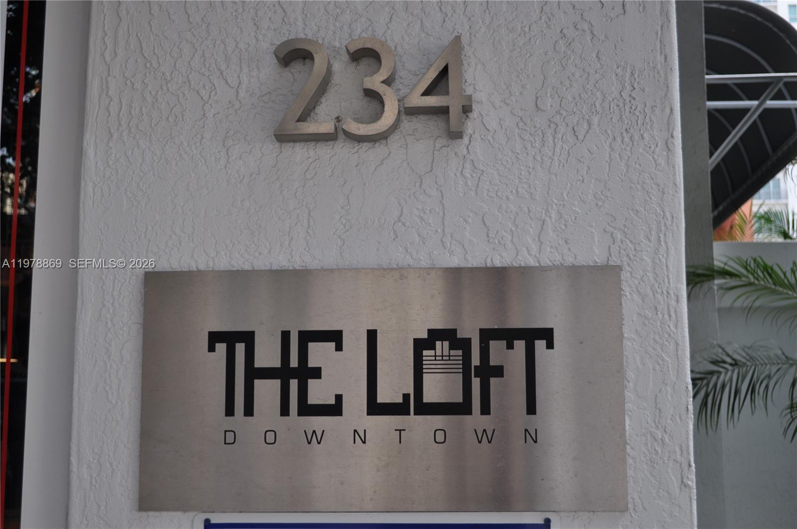 A metal sign reading The Loft Downtown is mounted on a textured white exterior wall — 234 NE 3rd St # 908, Miami FL 33132, MIAMI, FL