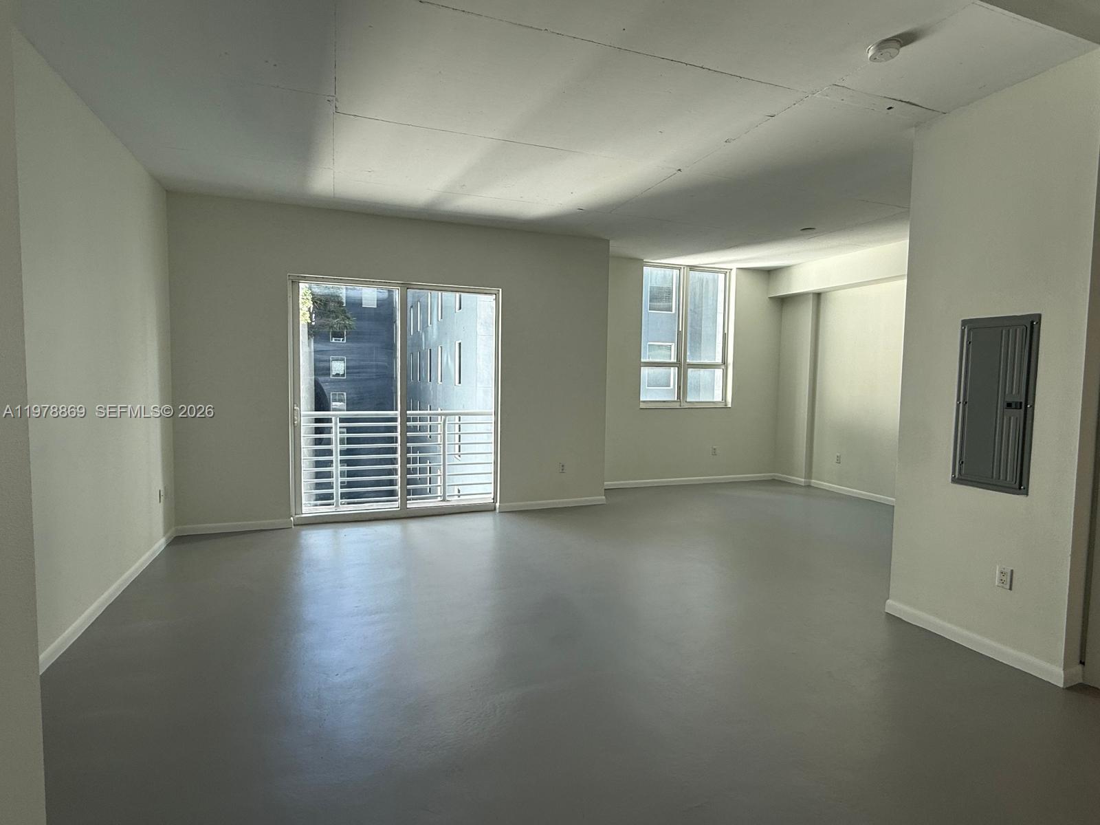 An empty living area features gray concrete floors, white walls, and a sliding glass door — 234 NE 3rd St # 908, Miami FL 33132, MIAMI, FL