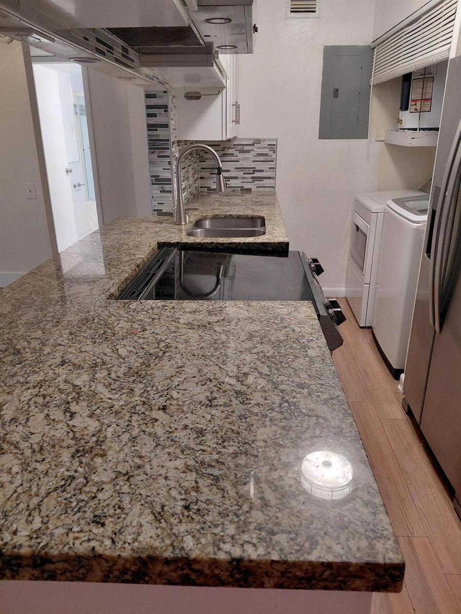 A kitchen features granite countertops, a glass-top stove, a stainless steel sink, and laundry appliances — 4525 NW Treehouse Lane # A, Tamarac FL 33319, TAMARAC, FL