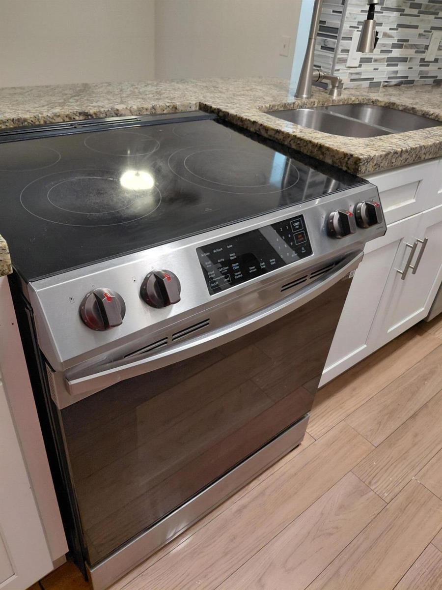 A stainless steel electric range is positioned next to a kitchen sink and granite countertop — 4525 NW Treehouse Lane # A, Tamarac FL 33319, TAMARAC, FL