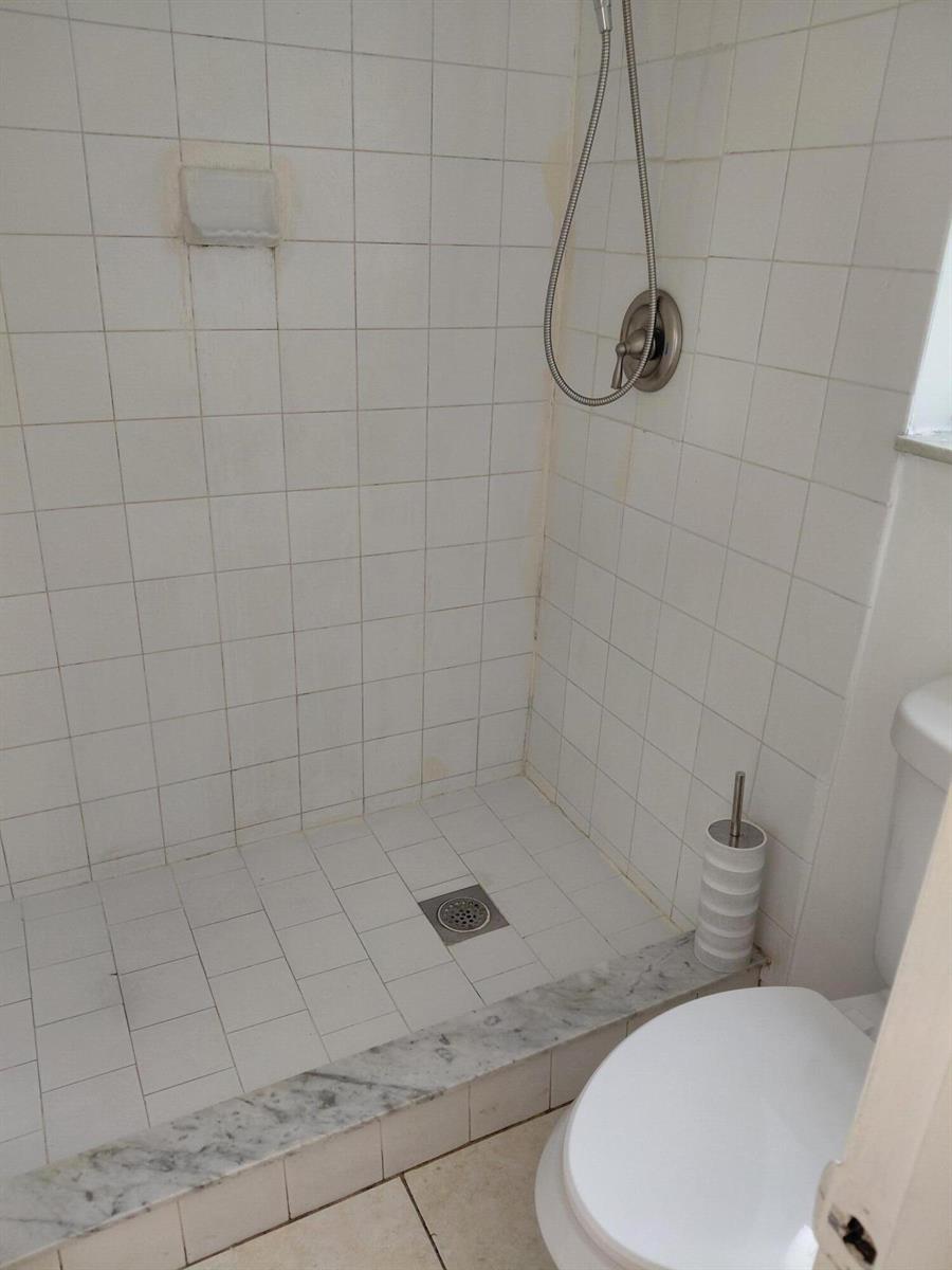 A walk-in shower with white tiled walls and floor, a handheld sprayer, and marble threshold — 4525 NW Treehouse Lane # A, Tamarac FL 33319, TAMARAC, FL