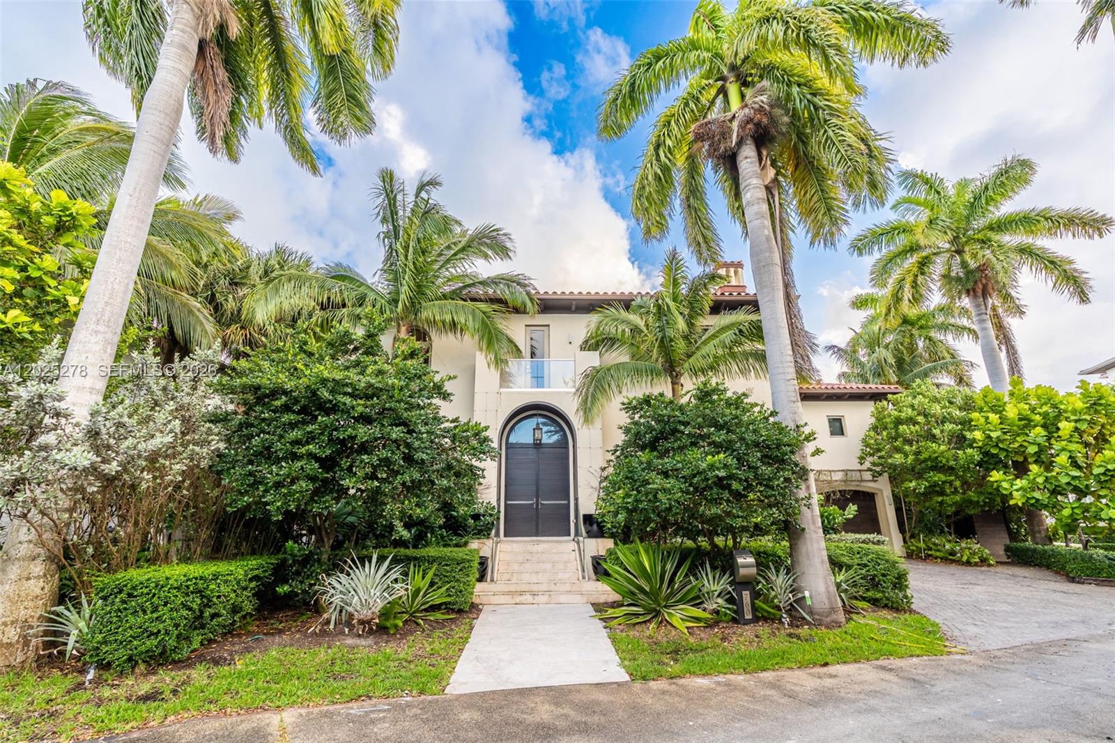 A two-story Mediterranean-style house features a grand arched entryway, palm trees, and lush landscaping — 760 S Mashta Dr, Key Biscayne FL 33149, KEY BISCAYNE, FL