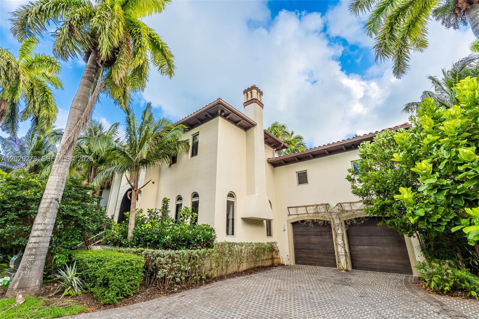 A two-story stucco house features a two-car garage, arched windows, and a chimney — 760 S Mashta Dr, Key Biscayne FL 33149, KEY BISCAYNE, FL