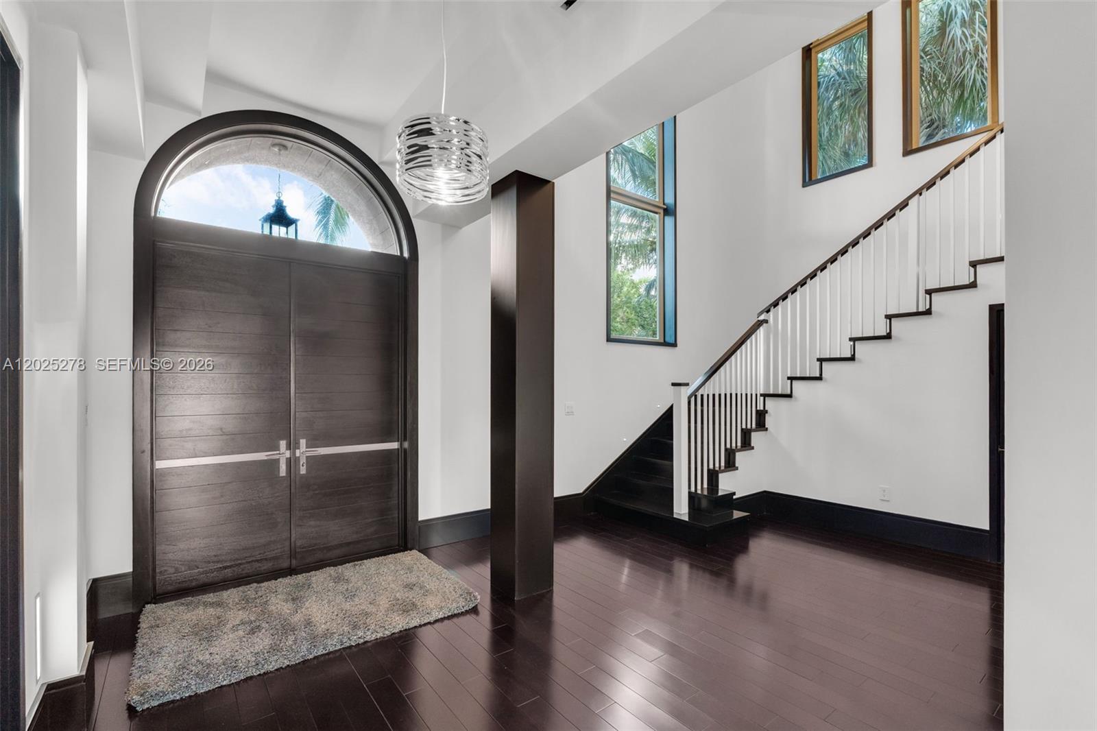 A modern foyer features a dark wood door, a staircase, and dark hardwood flooring — 760 S Mashta Dr, Key Biscayne FL 33149, KEY BISCAYNE, FL