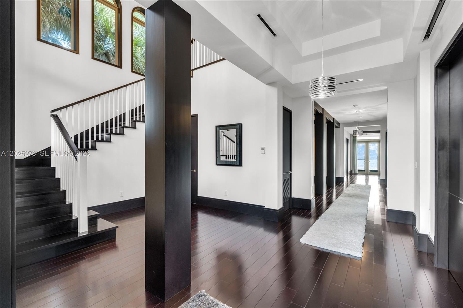 A bright foyer features dark hardwood floors, a staircase with white railings, and a long hallway — 760 S Mashta Dr, Key Biscayne FL 33149, KEY BISCAYNE, FL