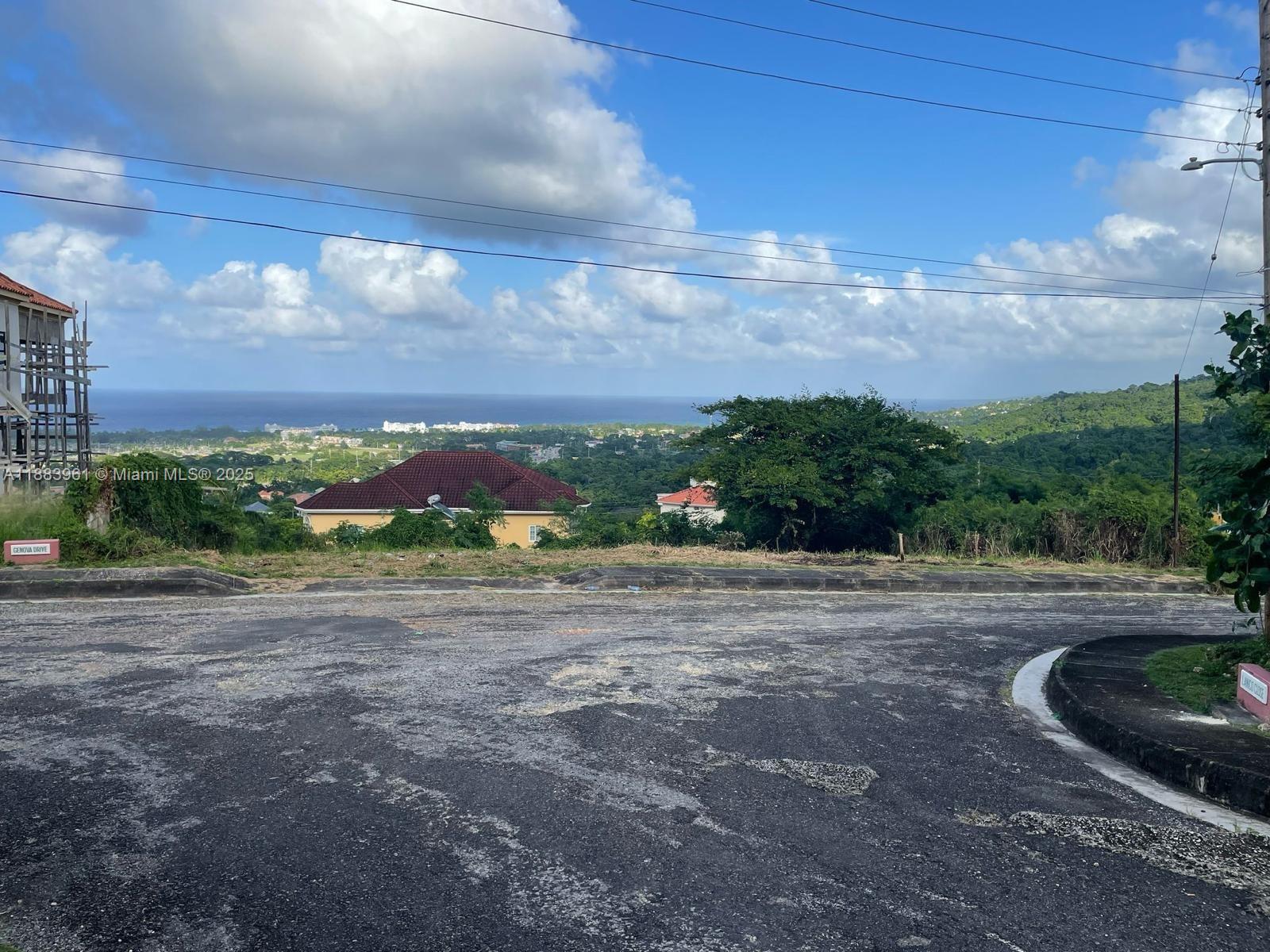 A paved road overlooks a hillside landscape with houses and a distant ocean view — 00 Vista Del Mar, Drax Hall St Ann Jamaica, NA, NA