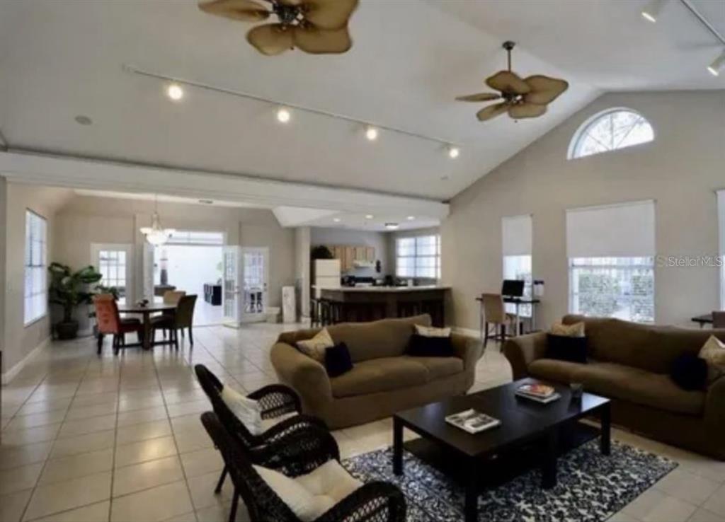 A spacious open-concept living room with tile floors, vaulted ceilings, and a kitchen in back — 3827 BAY CLUB CIRCLE UNIT 204, KISSIMMEE, FL