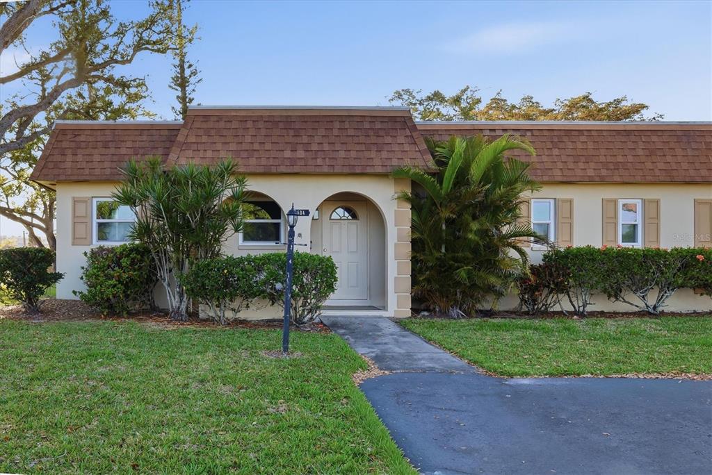 A single-story building with a brown mansard roof sits beside a large tree and driveway — 3504 38TH STREET W, BRADENTON, FL