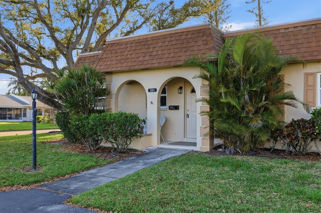 A single-story residential building features a tan stucco facade, arched entryway, and brown shingled roof — 3504 38TH STREET W, BRADENTON, FL
