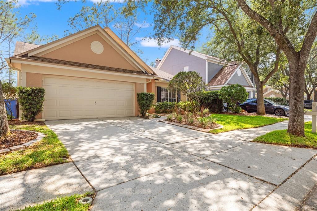 A tan house with a two-car garage and a concrete driveway under a blue sky — 9403 WILLOW COVE COURT, TAMPA, FL