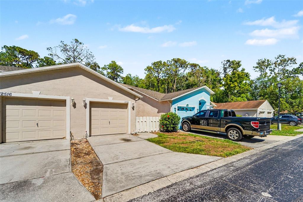 A duplex with two garage doors and a pickup truck parked in the driveway — 12514 HOLLYBROOK LANE, HUDSON, FL