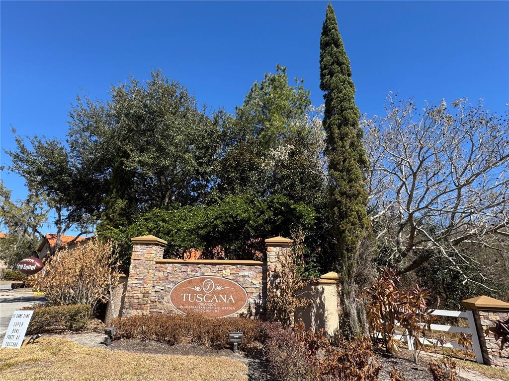 A stone monument sign for Tuscana Orlando stands in front of trees and a blue sky — 1301 TUSCAN TERRACE UNIT 9301, DAVENPORT, FL