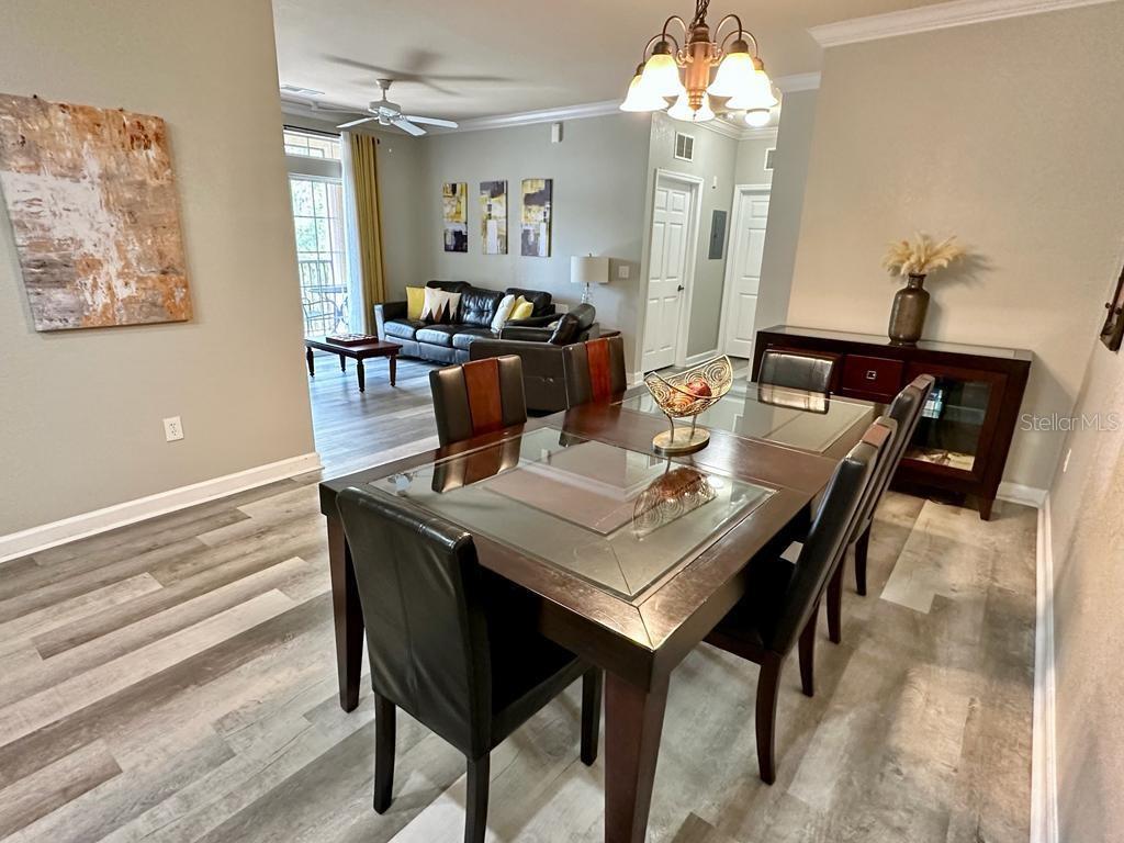 A dining room with a glass-topped table leads into a living area with gray flooring — 1301 TUSCAN TERRACE UNIT 9301, DAVENPORT, FL