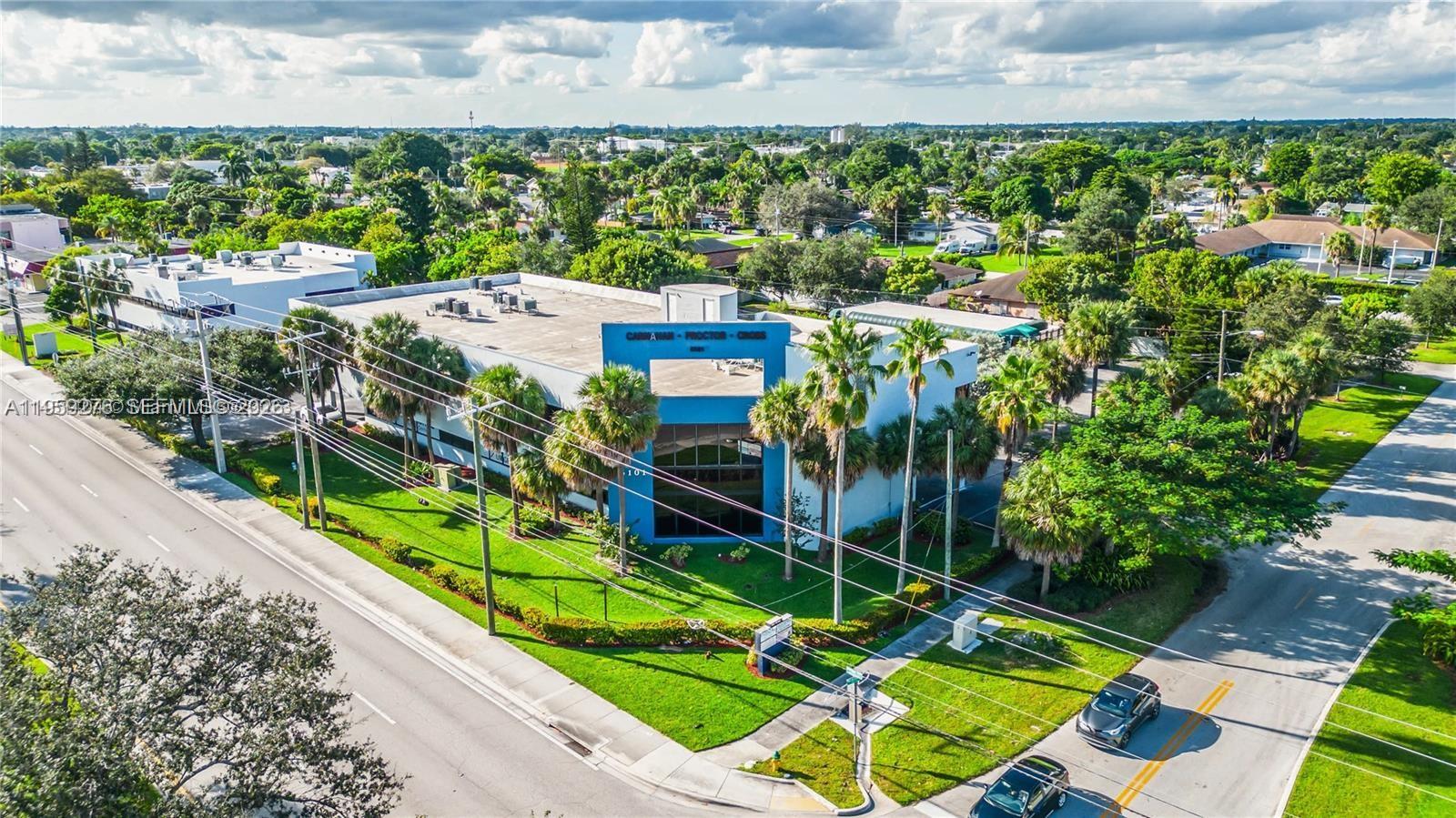An aerial view shows a blue and white commercial building surrounded by palm trees — 6101 W Atlantic Blvd # 213, Margate FL 33063, MARGATE, FL