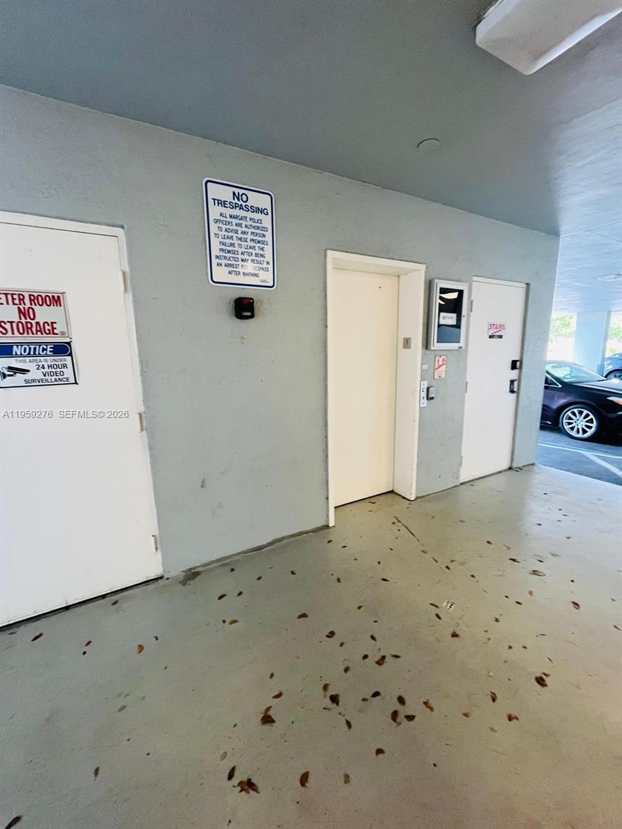 A concrete parking area features a meter room, an elevator, and a stairwell door — 6101 W Atlantic Blvd # 213, Margate FL 33063, MARGATE, FL