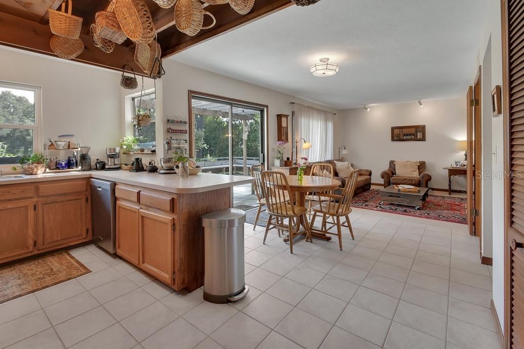 An open-concept kitchen and living area features light tile floors, wood cabinets, and hanging baskets — 1379 TAYLOR ROAD W, DELAND, FL