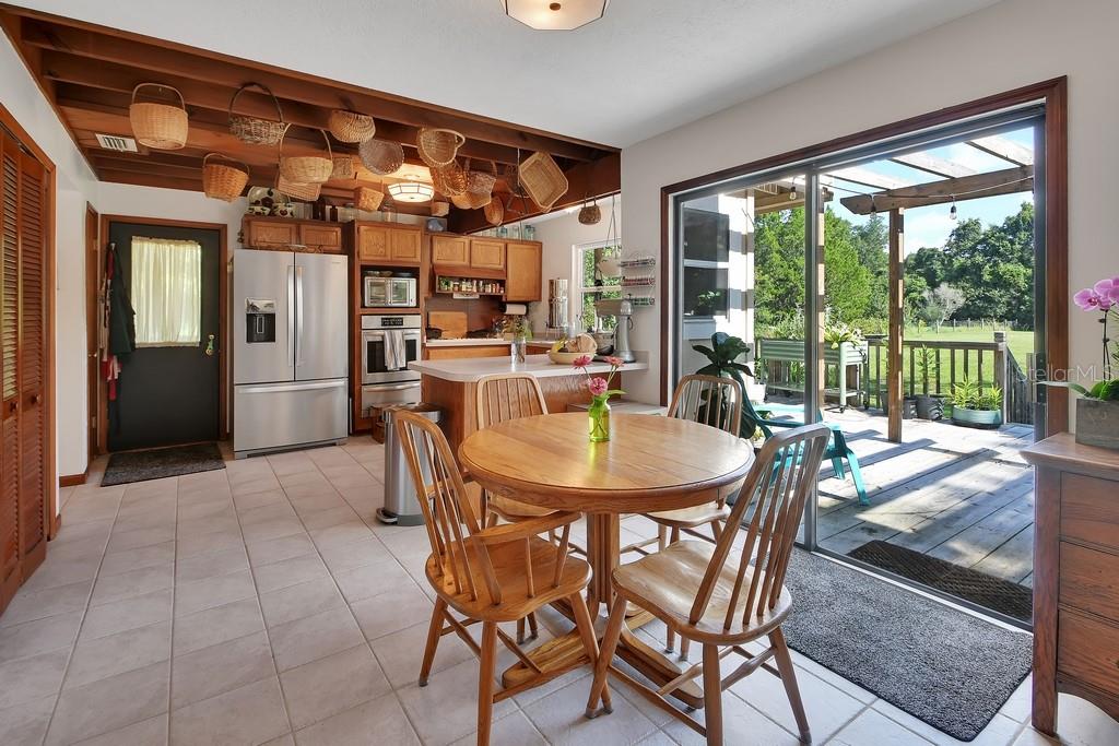 A kitchen with wooden ceiling beams, hanging baskets, tile floors, and a sliding glass door — 1379 TAYLOR ROAD W, DELAND, FL