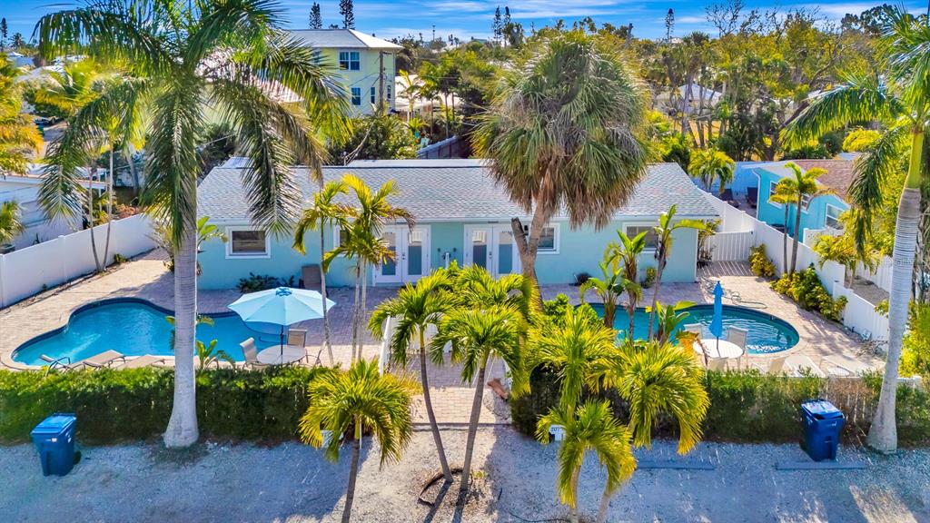 An aerial view of a light blue house with two swimming pools and palm trees — 207 75TH STREET UNIT B, BRADENTON BEACH, FL