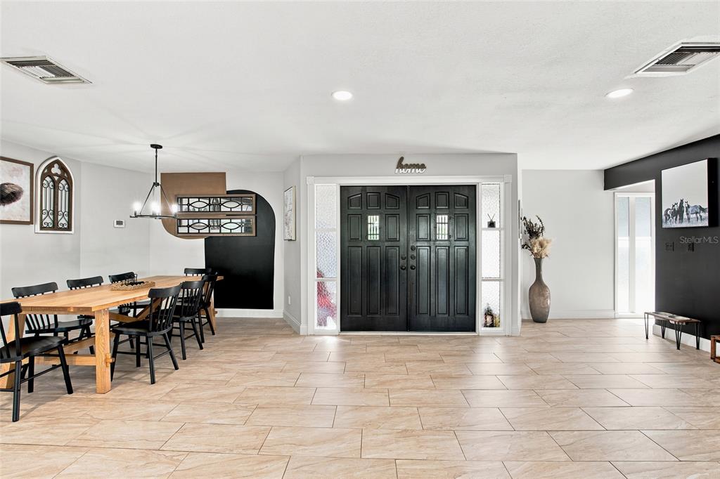 A dining area with a wooden table and black chairs sits beside a black double-door entrance — 224 N MCGOWAN AVENUE, CRYSTAL RIVER, FL