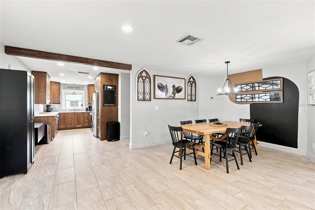 A dining area with a wooden table and black chairs sits adjacent to a kitchen — 224 N MCGOWAN AVENUE, CRYSTAL RIVER, FL