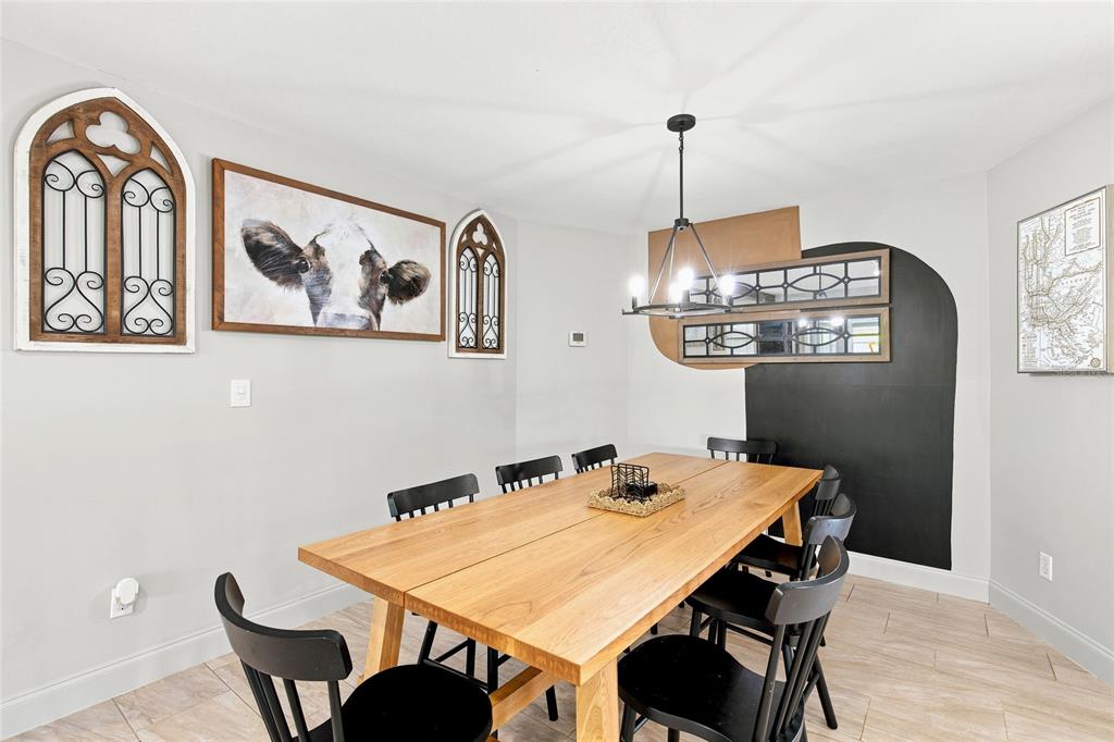 A dining room features a wooden table, black chairs, wall art, and a black accent wall — 224 N MCGOWAN AVENUE, CRYSTAL RIVER, FL