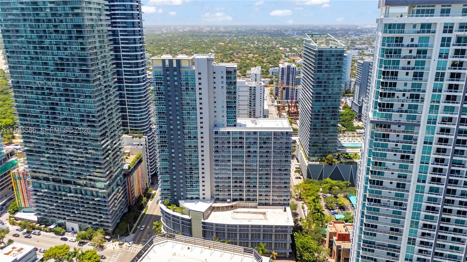 An aerial view shows several tall glass skyscrapers surrounding a lower-rise building in a city — 1250 S Miami Ave # 3506, Miami FL 33130, MIAMI, FL